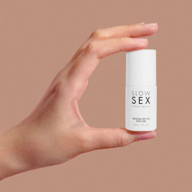 Flacon compact de l'huile au CBD Slow Sex tenu entre le pouce et l'index