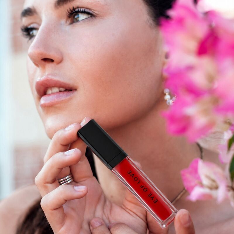 Femme tenant le gloss Crimson Kiss Eye Of Love près de son visage