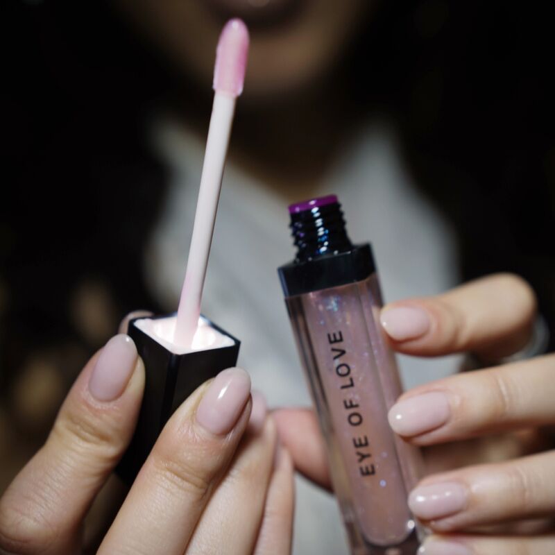 Main ouvrant le gloss Pink Pulse Eye Of Love et son applicateur rose